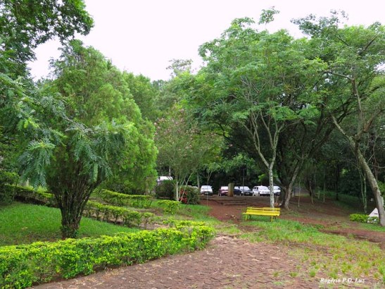 a praça, infelizmente, mal cuidada, e ao fundo o estacionamento para veículos