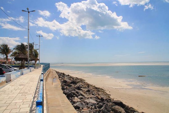 Muralha de pedra na praia tenta conter fortes erosões devido a combinação de marés e ondas fortes. A região como o município de Macau venta muito, bom para as salinas e o funcionamento de eólicas para gerar energia, mas também tem seu preço.