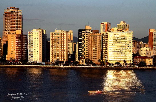 Prédio em Santos reflete a luz do sol na água em fim de tarde 