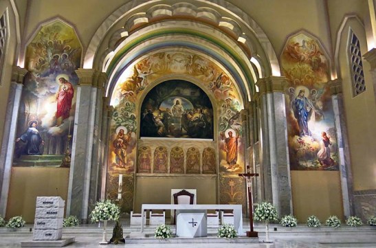 "Em 1951, Aldo Locatelli inicia as pinturas da Igreja com o mural da Santa Ceia, de 90 metros quadrados de área, ladeada pela Aparição do Sagrado Coração de Jesus a Santa Margarida Maria Alecoque, à esquerda, e a Aparição de Nossa Senhora de Caravaggio à vidente Joaneta, à direita."