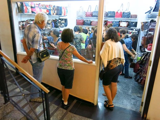 Uma parada numa galeria de lojas com uma delas a promover uma liquidação de bolsas, para alegria das senhoras excursionistas