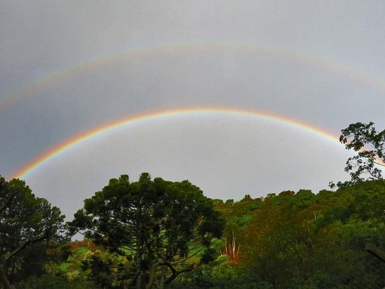 Um duplo arco-íris apresenta as cores invertidas no arco secundário (o arco superior na foto).